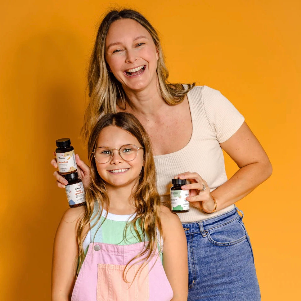 Woman and child holding bottles against an orange background