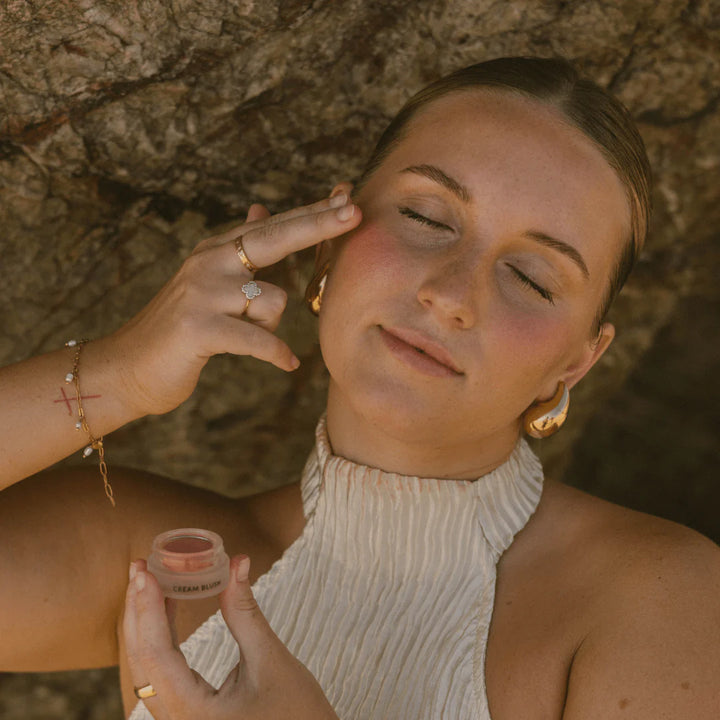 Woman applying makeup with a small container outdoors