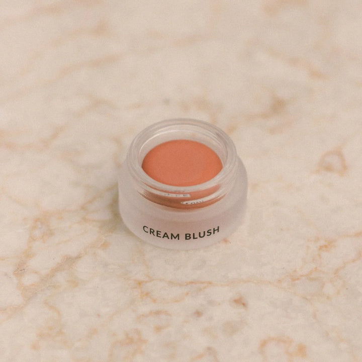 Jar of cream blush on a marble surface