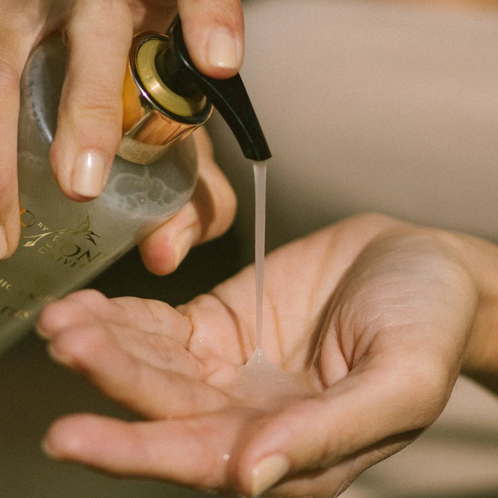 Hand holding a bottle of skincare product with dropper over another hand