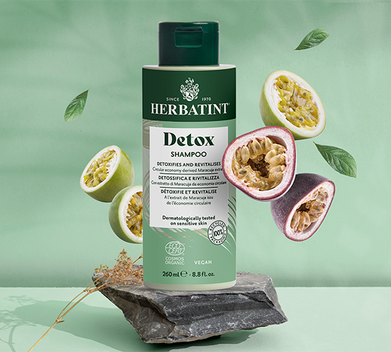 Herbatint Detox Shampoo bottle with passion fruit slices on a green background