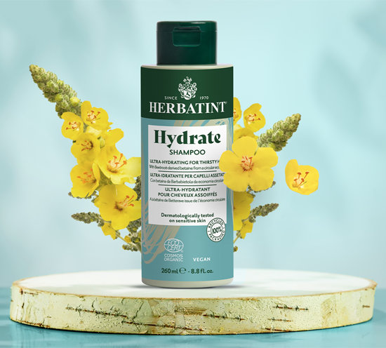 Herbatint Hydrate Shampoo bottle with yellow flowers on a light blue background
