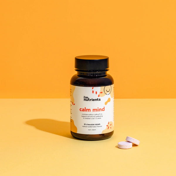 Bottle of 'calm mind' supplements with two tablets on an orange background