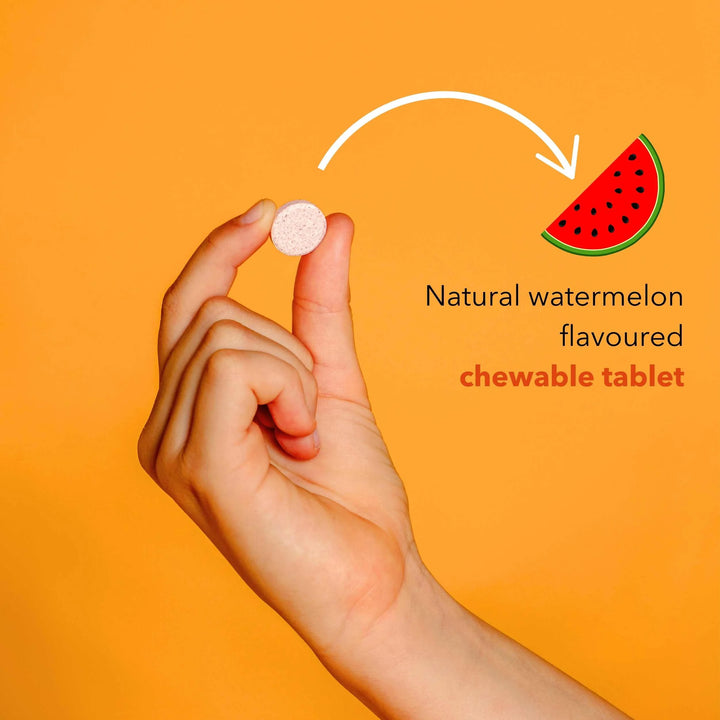 Hand holding a chewable tablet with watermelon flavor on an orange background