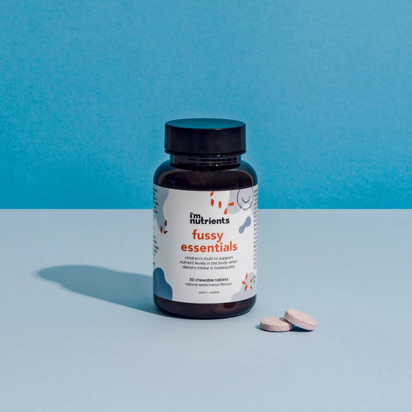 Bottle of 'fussy essentials' supplements with two tablets on a blue background